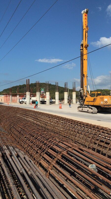 Máquina perforadora amarilla trabajando en cimentación de puente vial